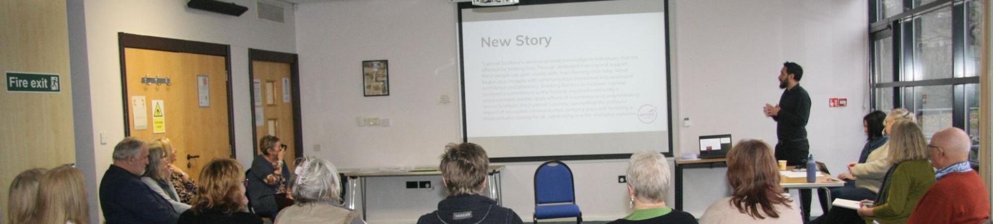 Presenter delivering a talk to seated audience with projected slides